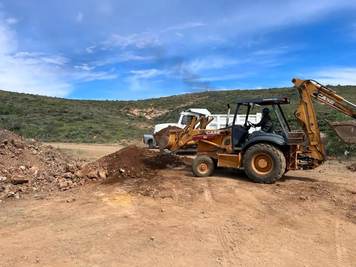 Retroexcavadora cargando material a granel en una unidad