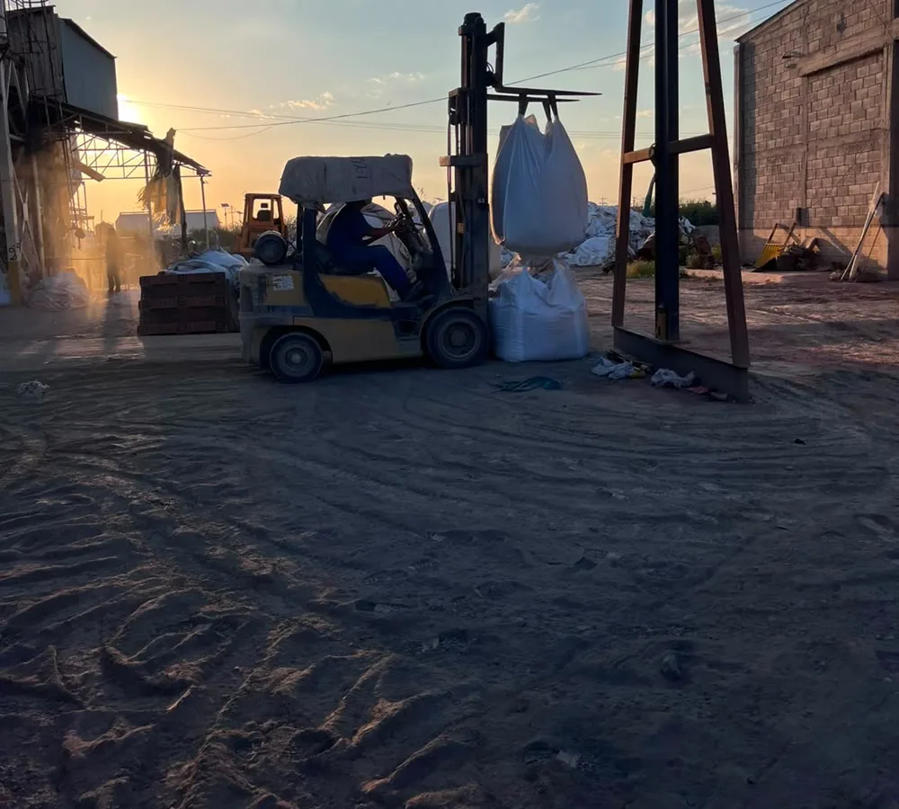 Montacargas con big bag de mineral en patio de acopio al atardecer