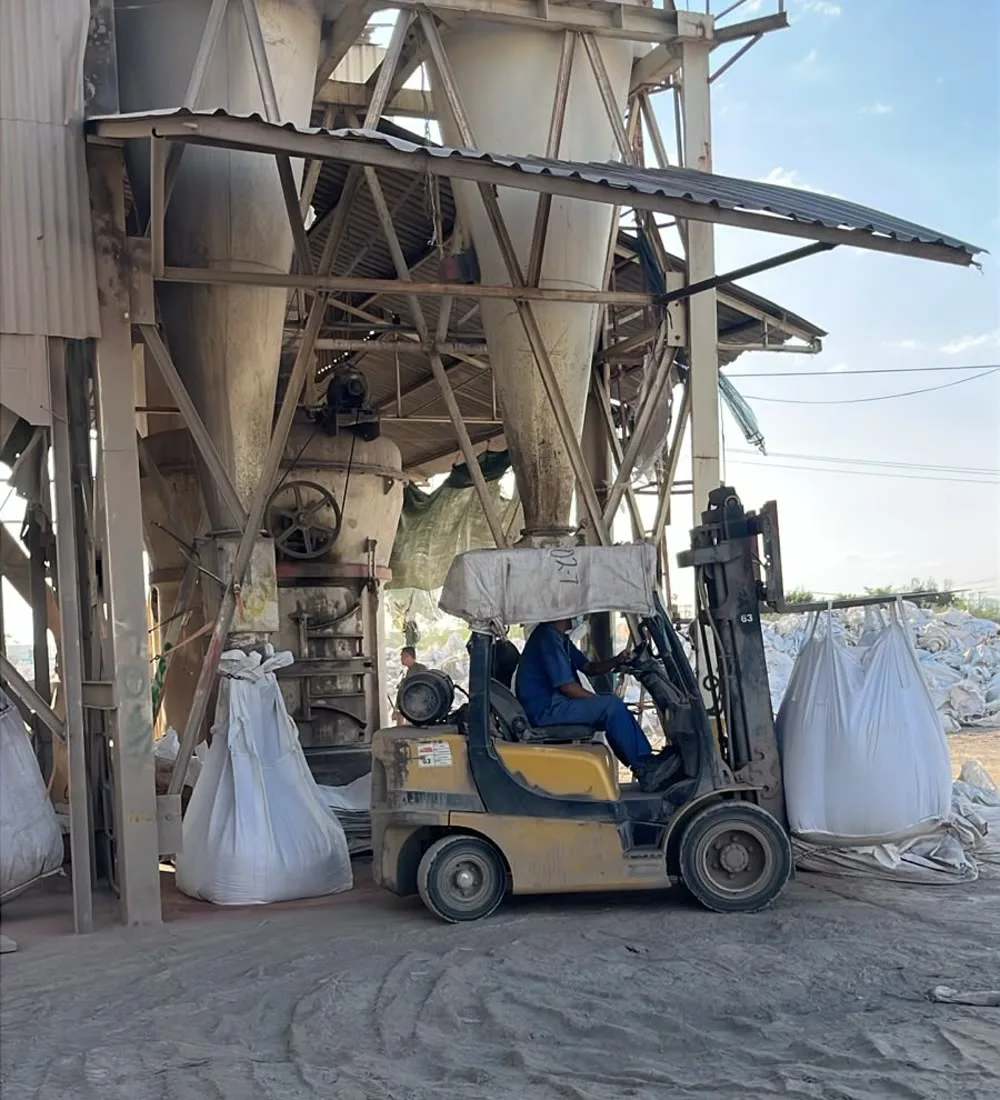 Montacargas moviendo big bags en planta de proceso con silos